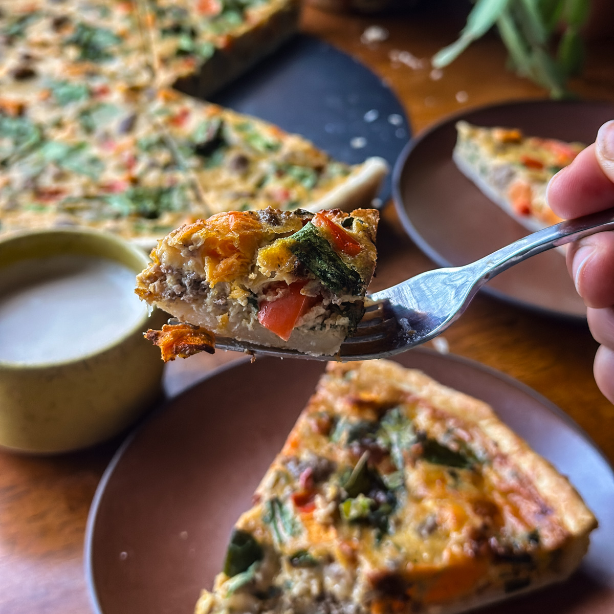 taking a bite of sausage and veggie quiche